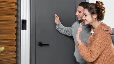2 people waving into the Aqara Video Doorbell G4