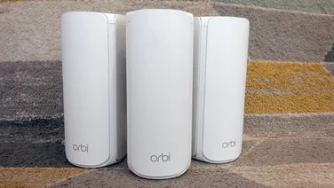 Three Netgear Orbi 770 units pictured on a yellow and grey rug