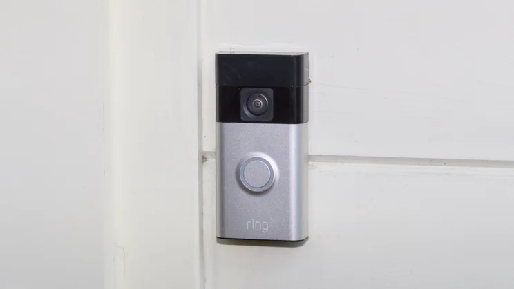 The Ring Battery Video Doorbell pictured mounted on a cream wood wall