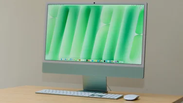 The M4 Apple iMac in green, pictured on a wood table with matching keyboard and mouse
