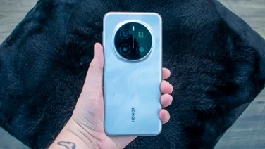 Honor Magic 7 Pro in hand, rear view, in front of a black cushion