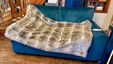 Dreamland Hygge Days Faux Fur Luxury Heated Throw review layed out on a blue sofa