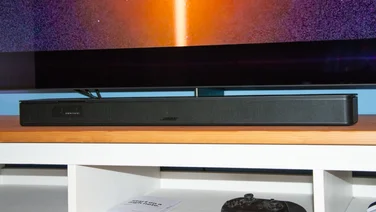 bose_smart_soundbar_review_featured under a tv on a wooden tv stand