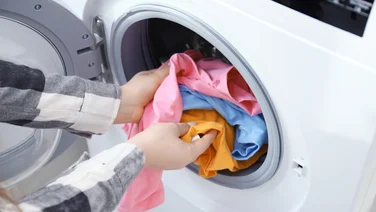 ehumidifiers v tumble dryers woman placing clothes into a machine