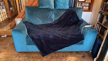Lakeland StaySnug Velvety Navy Heated Throw teaser blue throw layed out on a blue sofa