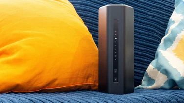 The Netgear RS200 wireless router on a blue sofa next to some brightly coloured cushions