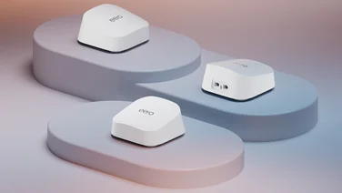 Three Eero 7 routers, positioned on a white stage