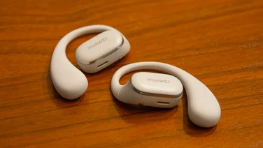 The Huawei FreeArc open-ear headphones on a wooden table
