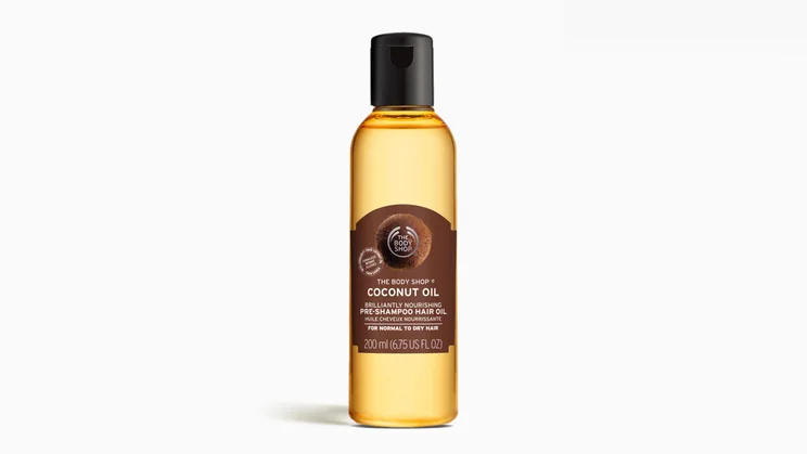 The Body Shop Coconut Oil Brilliantly Nourishing Pre-Shampoo Hair Oil on a grey background