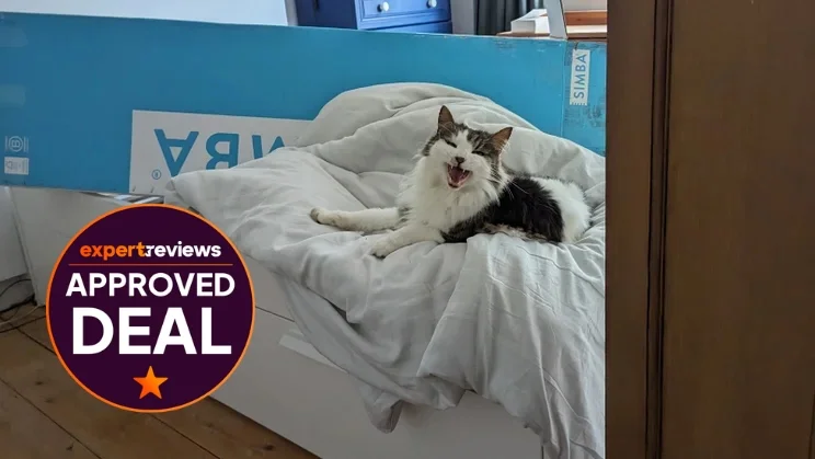 A cat sits on a duvet on top of a bed, with a Simba box behind it. In the corner is a circular badge reading "Expert Reviews approved deal"
