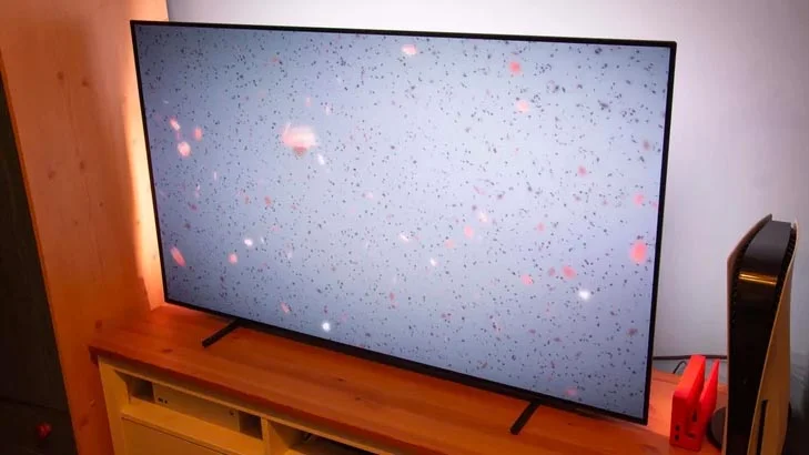 The Philips OLED760 TV on a TV cabinet alongside a Nintendo Switch and PlayStation 5