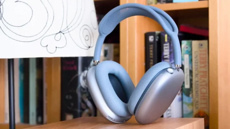 The Apple AirPods Max 2 over-ear headphones on a chair in front of a bookshelf