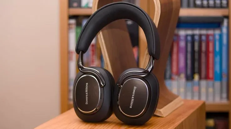 The Bowers & Wilkins Px8 S2 over-ear headphones on a chair in front of a bookshelf