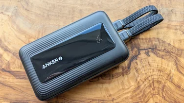 The Anker Zolo A1680 power bank pictured from above with two USB-C cables connected, on a walnut tabletop