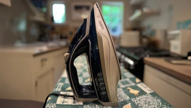 Beldray Precision1 steam iron upright on a colourful ironing board cover