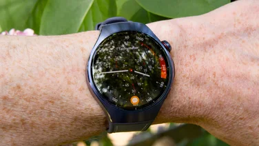 The Huawei Watch 5 being worn on wrist with some greenery in the background