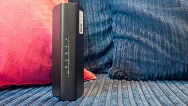 Netgear Nighthawk RS100 pictured upright on a blue textile surface with pillow in the background