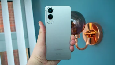 Samsung Galaxy S25 Edge in hand, rear view, in front of a light fixture and open blinds