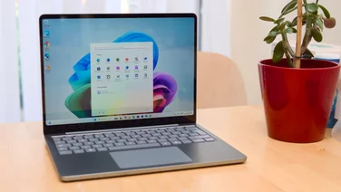 The Microsoft Surface Laptop 13in, pictured on a table next to a house plant in a red pot