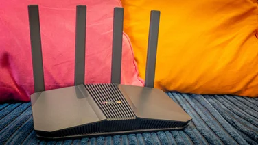 The Asus RT-BE58U pictured from the front against a colourful background