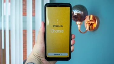 Chatsie Phone in hand, with the display on, in front of a window
