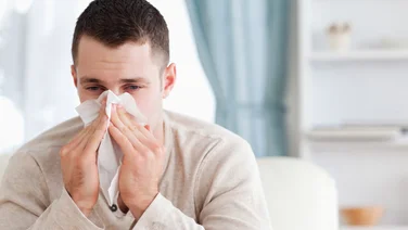 A man blowing his nose in a living room