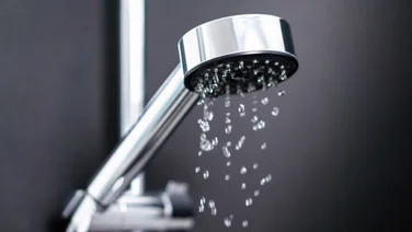 Last drops of water splash from shower head.