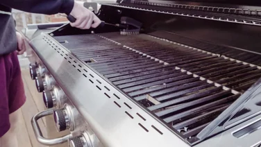How to keep your BBQ clean, person cleaning a bbq