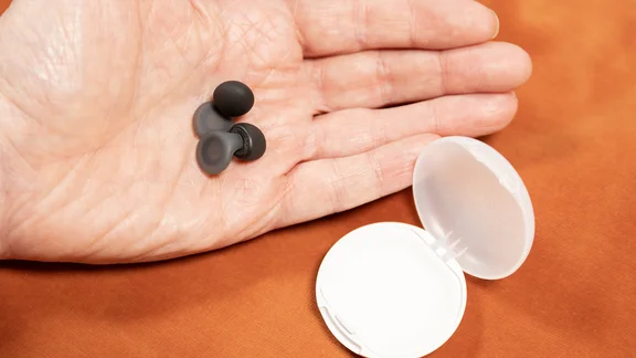 The Loop Dream earplugs resting in an open palm, beside their open case