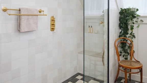 White shower room with chequerboard floor and brass concealed fittings