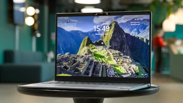 The Dell 14 Plus laptop, open, pictured from the front right corner on a small black circular coffee table