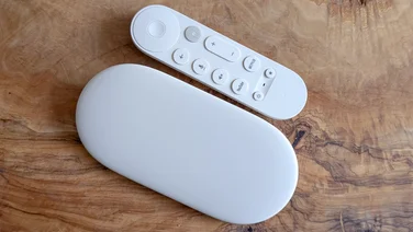 The Google TV Streamer 4K pictured from above next to its remote control