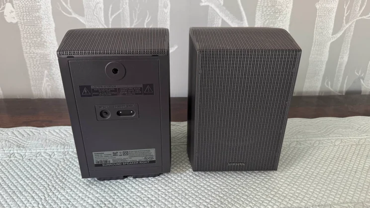 An image showing one of the rear speakers included in the Samsung HW-Q990F home audio system facing forwards and the other facing backwards