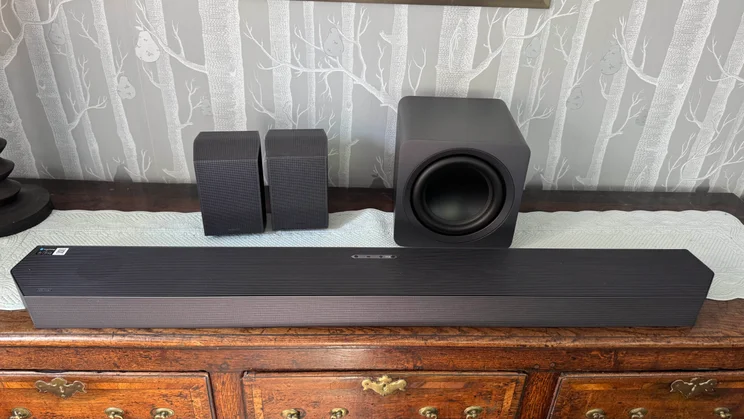 Front view of the Samsung HW-Q990F soundbar, subwoofer and rear speakers on a wooden dresser