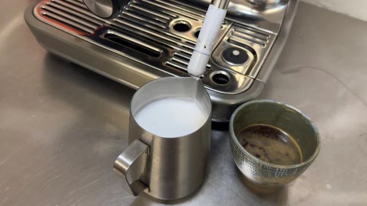 A jug of milk, just after having been steamed using the Sage Barista Touch Impress coffee machine