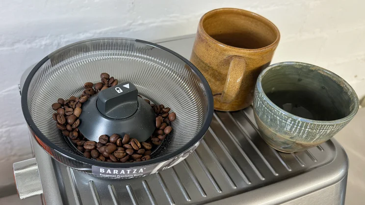 A close up of the Sage Barista Touch Impress' bean hopper with two cups on the warmer tray