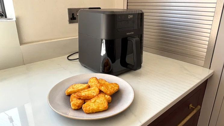 A plate of cooked hash browns on a kitchen counter, alongside the Instant Pot Vortex Compact 5L air fryer