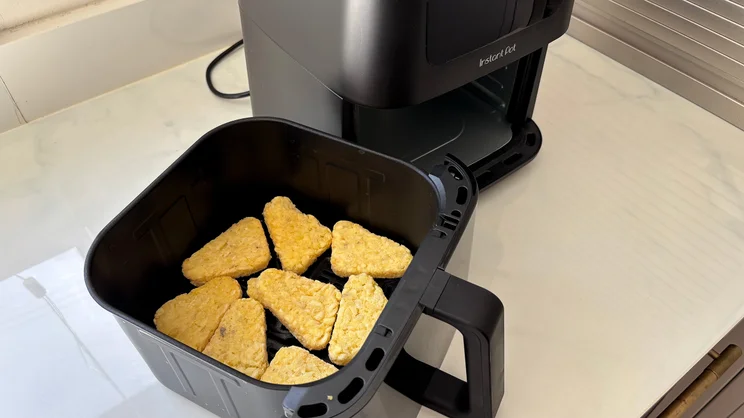 Uncooked hash browns inside the drawer of the Instant Pot Vortex Compact 5L air fryer