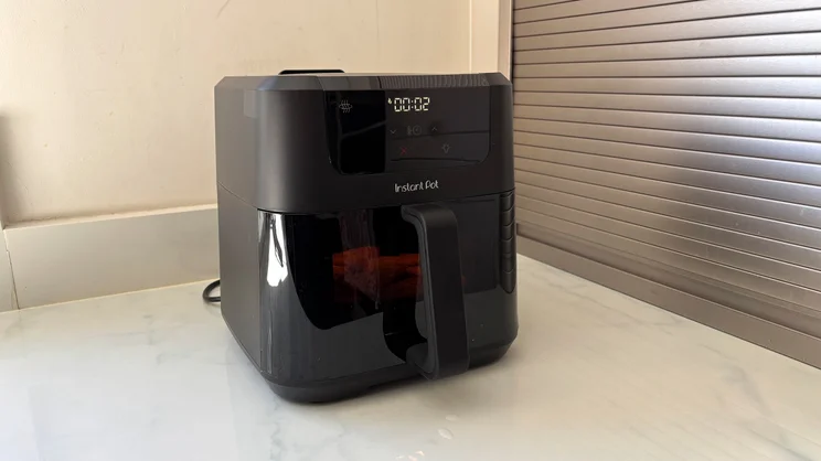 The Instant Pot Vortex Compact 5L air fryer on a kitchen counter, with hash browns cooking inside