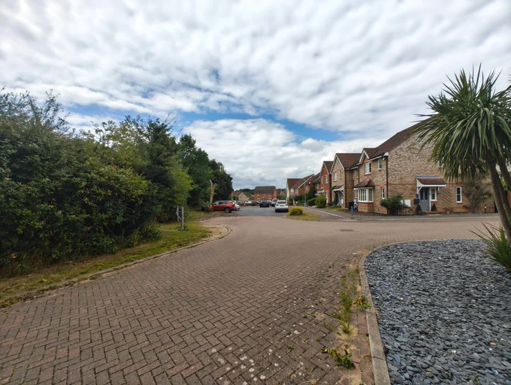 Wide-angle shot of a group of houses with cars parked out front