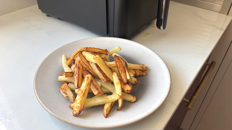 Cooked chips on a plate, next to the Tower Vortx 11 Litre Dual Layer air fryer