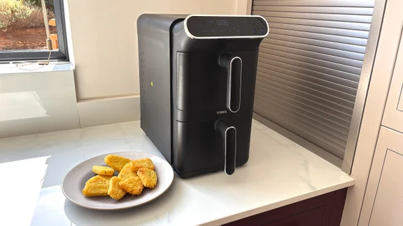 The Tower Vortx 11 Litre Dual Layer air fryer on a kitchen counter, alongside a plate of cooked hash browns