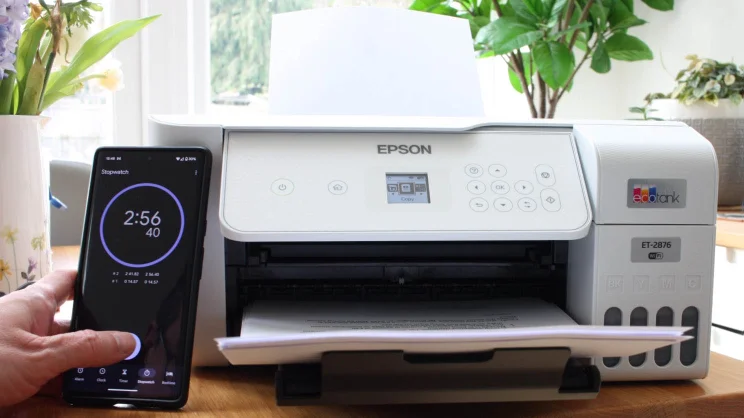 A colour printer being tested by a man holding a smartphone