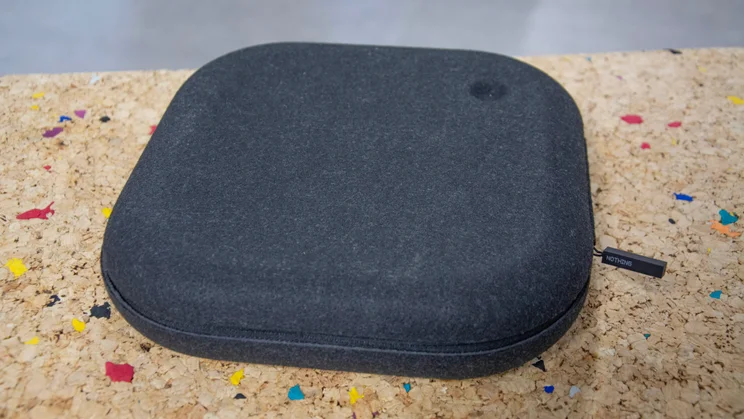 The carrying case included with the Nothing Headphone (1) on a cork table