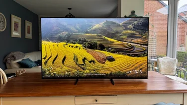 Front view of the Sony Bravia 9 Mini LED TV displaying a screensaver while located on a wooden table in a kitchen