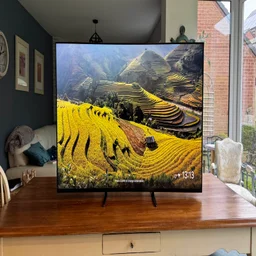 Front view of the Sony Bravia 9 Mini LED TV displaying a screensaver while located on a wooden table in a kitchen