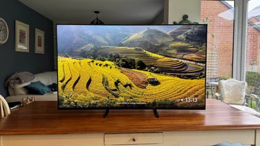 Front view of the Sony Bravia 9 Mini LED TV displaying a screensaver while located on a wooden table in a kitchen