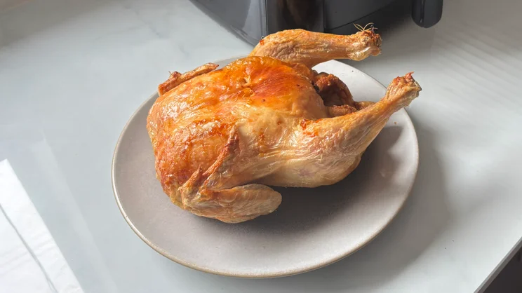 A roast chicken on a plate, after having been cooked in the Bosch Series 6 Air Fryer