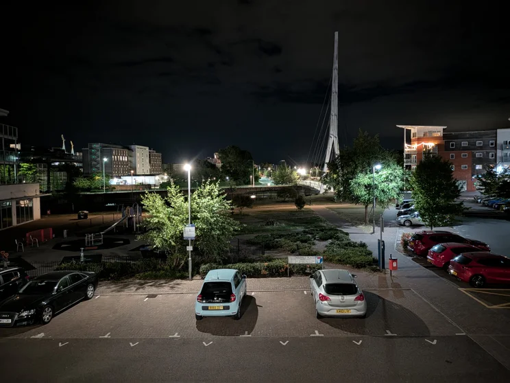 A car park at night, flat blocks all around it