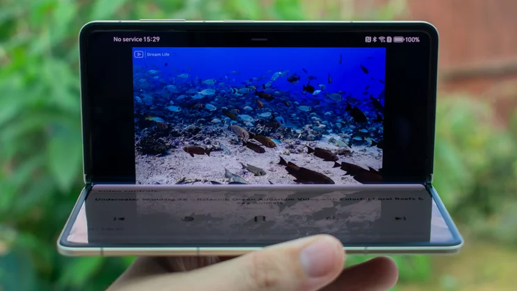 Honor Magic V5 folded 90 degrees in hand, with a video on the display